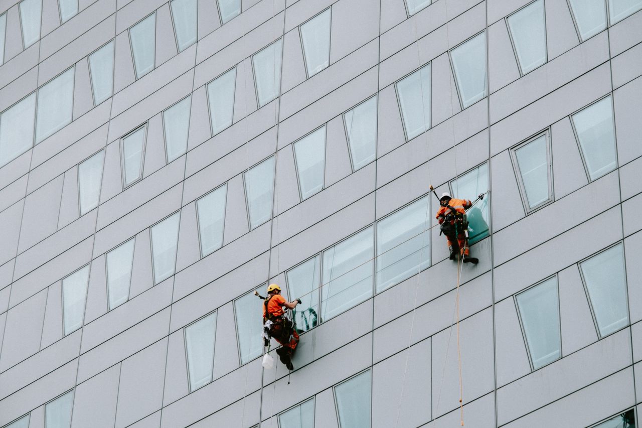 services-01 High-rise window cleaners in protective gear cleaning the facade of a skyscraper.